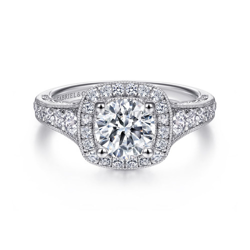 vintage-inspired halo engagement ring with round moissanite center stone and diamond accented halo and band with scrollwork detailing beneath the center stone