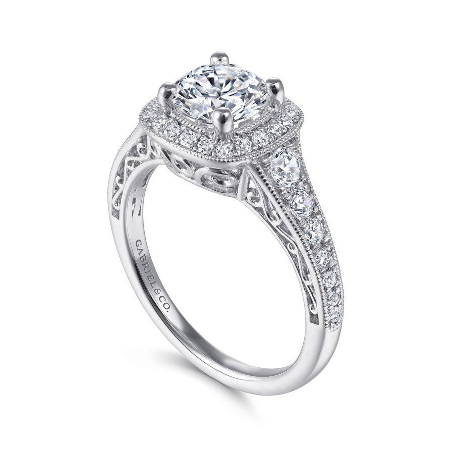 vintage-inspired halo engagement ring with round moissanite center stone and diamond accented halo and band with scrollwork detailing beneath the center stone