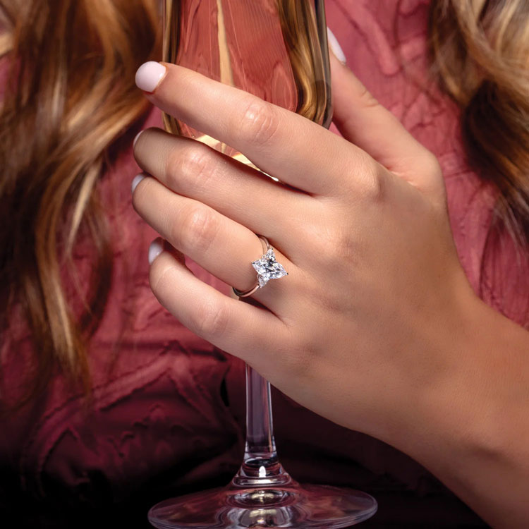 three-stone engagement ring with polished band and pear-shaped diamond accent stones