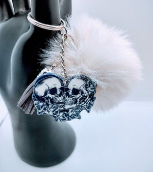 Till Death Lovers Acrylic Keychain With Fur And Tassel. Acrylic Keychain is made with 100% premium acrylic and features two Skeleton skull heads kissing in love. This keychain makes the perfect gift for all. Our designers carefully choose every material to bring you the best quality and craftsmanship possible. Though the color of the fur may vary upon delivery due to availability, each keychain features an original unique design.