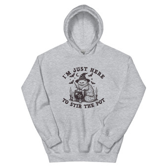 Halloween hoodie featuring a witchy black cat wearing a hat and stirring a cauldron, with the phrase “I’m just here to stir the pot.” Playful spooky design.