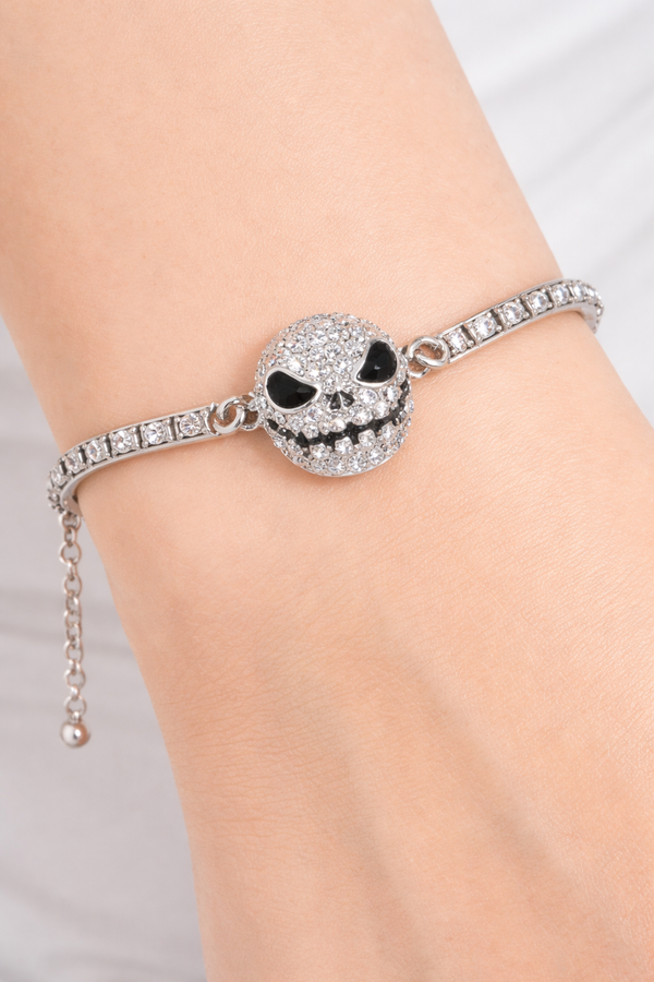 Features a rhinestone skull bracelet showcased across multiple views, including a crisp white background product shot, a clean display stand image for structure and shape, a close-up worn-on-wrist lifestyle photo for scale, and a styled flat lay with dark, gothic-inspired elements to highlight its edgy aesthetic and sparkle.