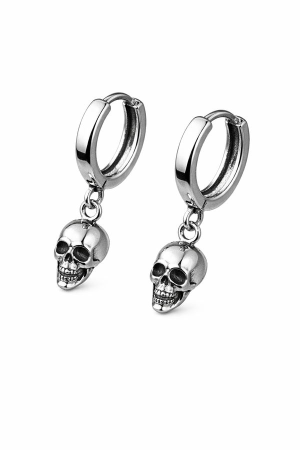 A pair of small silver skull huggie hoop earrings featuring polished metal hoops with detailed dangling skull charms. These lightweight earrings offer a subtle edgy look, combining minimalist size with gothic-inspired design. Perfect for everyday wear, they add a touch of alternative style while remaining versatile and easy to pair with any outfit.