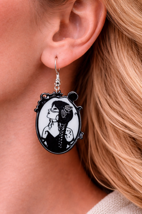A curated collection of witchy-inspired acrylic earrings featuring dark, mystical designs including celestial symbols, occult figures, crystal shapes, and gothic motifs. Each pair showcases bold black detailing paired with soft lavender accents, displayed in styled scenes with crystals, candles, and moody textures. The collection blends alternative fashion with mystical aesthetics, creating a cohesive, edgy yet feminine visual