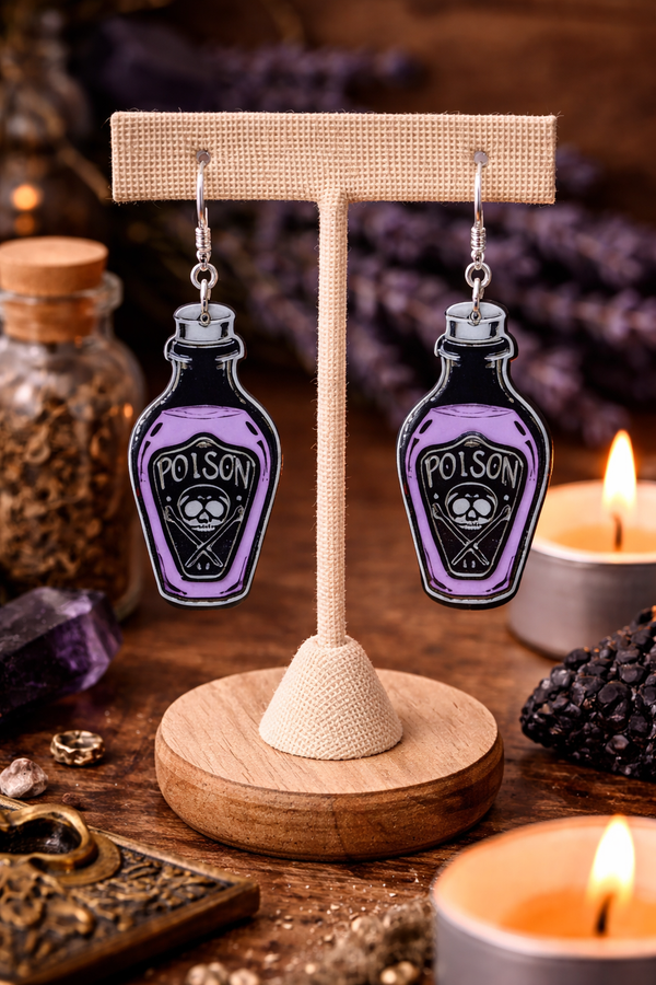 A curated collection of witchy-inspired acrylic earrings featuring dark, mystical designs including celestial symbols, occult figures, crystal shapes, and gothic motifs. Each pair showcases bold black detailing paired with soft lavender accents, displayed in styled scenes with crystals, candles, and moody textures. The collection blends alternative fashion with mystical aesthetics, creating a cohesive, edgy yet feminine visual