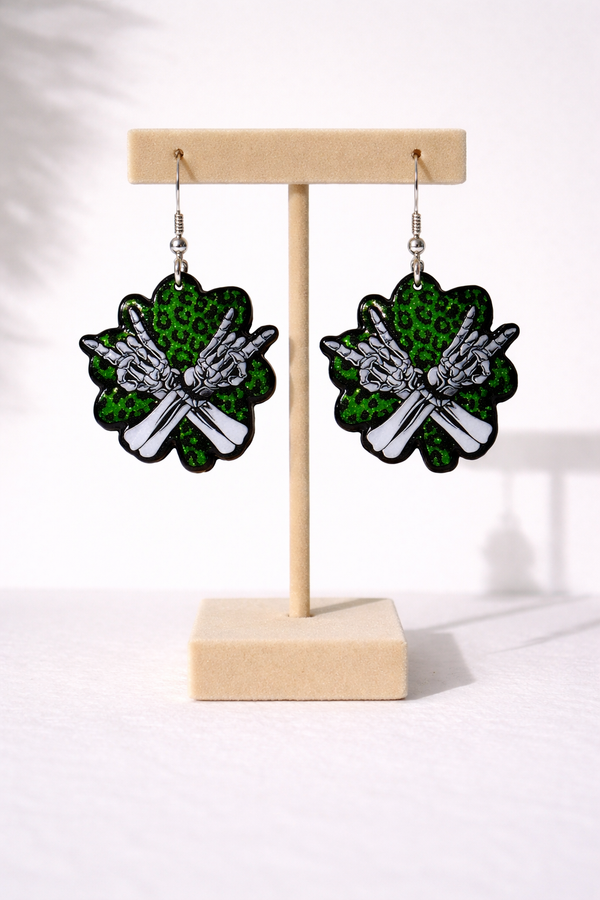 An assorted collection of St. Patrick’s Day-themed acrylic earrings featuring bold, edgy designs with skeletons, skulls, shamrocks, and leprechaun-inspired elements. Each pair showcases vibrant green accents paired with black and white detailing for a high-contrast, gothic-meets-festive aesthetic. Designs include skeleton hands, skull faces, clover details, and playful drinking motifs, all hanging from silver fishhook ear wires. This set blends dark humor, alternative style, and holiday spirit for a unique, statement-making accessory lineup.