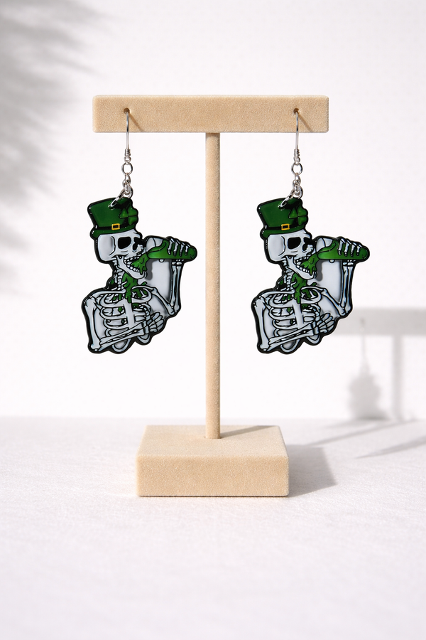 An assorted collection of St. Patrick’s Day-themed acrylic earrings featuring bold, edgy designs with skeletons, skulls, shamrocks, and leprechaun-inspired elements. Each pair showcases vibrant green accents paired with black and white detailing for a high-contrast, gothic-meets-festive aesthetic. Designs include skeleton hands, skull faces, clover details, and playful drinking motifs, all hanging from silver fishhook ear wires. This set blends dark humor, alternative style, and holiday spirit for a unique, statement-making accessory lineup.