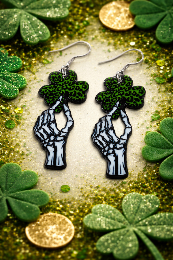 An assorted collection of St. Patrick’s Day-themed acrylic earrings featuring bold, edgy designs with skeletons, skulls, shamrocks, and leprechaun-inspired elements. Each pair showcases vibrant green accents paired with black and white detailing for a high-contrast, gothic-meets-festive aesthetic. Designs include skeleton hands, skull faces, clover details, and playful drinking motifs, all hanging from silver fishhook ear wires. This set blends dark humor, alternative style, and holiday spirit for a unique, statement-making accessory lineup.