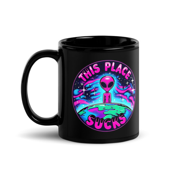 Black gloss ceramic mug displayed upright featuring a bright alien graphic with the phrase “This Place Sucks.” Bold neon colors pop against the black background. Shown with front-facing design for clear visibility.
