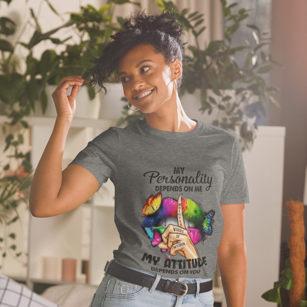 “My Personality Depends On Me My Attitude Depends On You graphic t-shirt featuring colorful neon lips with butterflies and finger whisper design, full view showing vibrant rainbow artwork on light heather gray shirt, perfect for bold inspirational statement wear.”