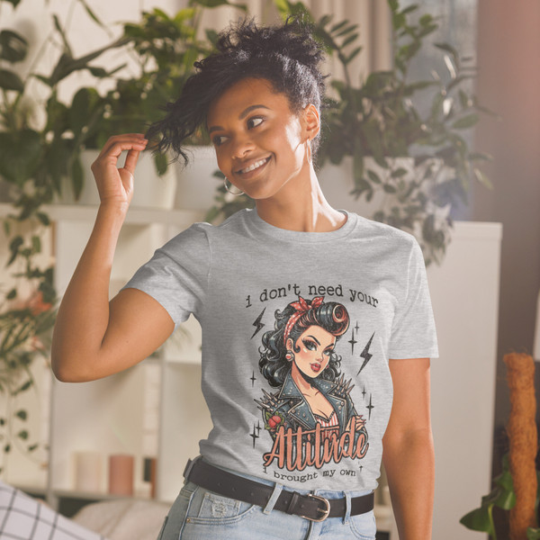 “I Don’t Need Your Attitude I Brought My Own retro pin-up graphic t-shirt featuring vintage rockabilly woman with leather jacket on sport grey shirt, full view showing bold red lettering and edgy statement design.”