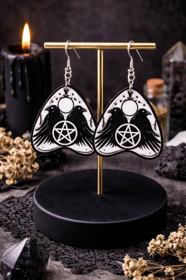 Collection of Ouija planchette acrylic earrings displayed in multiple design variations on a clean background. Each pair features unique lettering styles, symbols, and finishes while maintaining a cohesive dark, witchy aesthetic. The assortment highlights different options within the same occult-inspired theme.