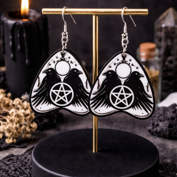 Collection of Ouija planchette acrylic earrings displayed in multiple design variations on a clean background. Each pair features unique lettering styles, symbols, and finishes while maintaining a cohesive dark, witchy aesthetic. The assortment highlights different options within the same occult-inspired theme.