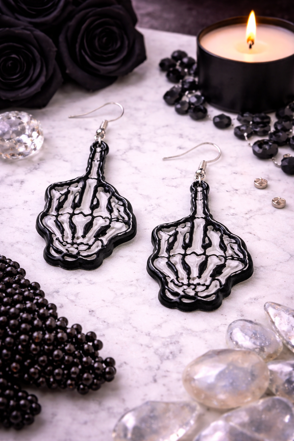 An assortment of edgy acrylic earrings featuring bold, rebellious designs including skeleton hands, sarcastic symbols, and attitude-driven graphics. Each pair showcases high-contrast detailing and expressive themes, styled against clean or minimal backgrounds to highlight their statement-making appeal.