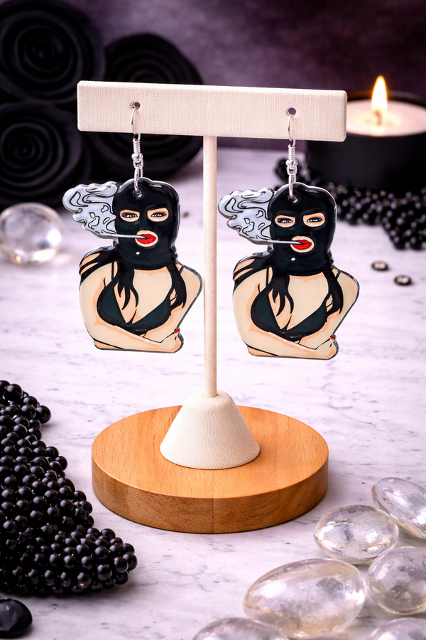 An assortment of edgy acrylic earrings featuring bold, rebellious designs including skeleton hands, sarcastic symbols, and attitude-driven graphics. Each pair showcases high-contrast detailing and expressive themes, styled against clean or minimal backgrounds to highlight their statement-making appeal.