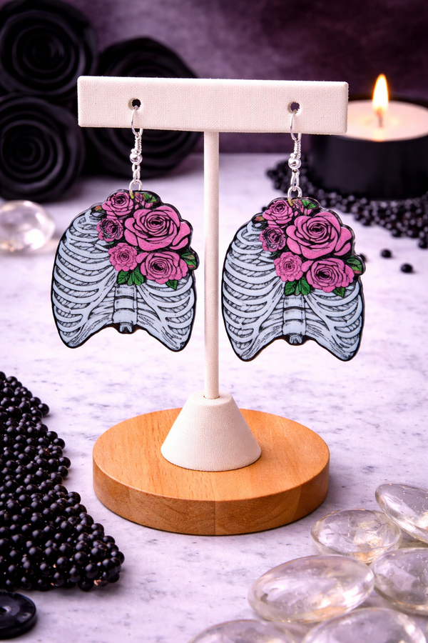 An assortment of edgy acrylic earrings featuring bold, rebellious designs including skeleton hands, sarcastic symbols, and attitude-driven graphics. Each pair showcases high-contrast detailing and expressive themes, styled against clean or minimal backgrounds to highlight their statement-making appeal.