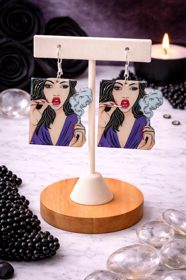An assortment of edgy acrylic earrings featuring bold, rebellious designs including skeleton hands, sarcastic symbols, and attitude-driven graphics. Each pair showcases high-contrast detailing and expressive themes, styled against clean or minimal backgrounds to highlight their statement-making appeal.