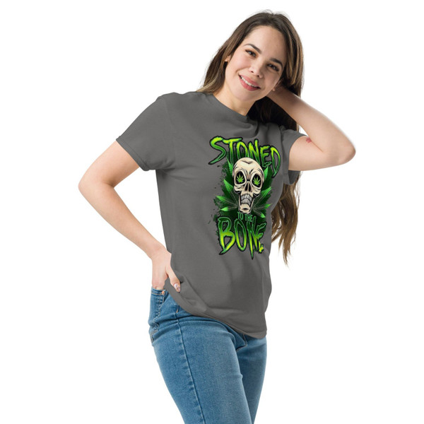 Charcoal gray unisex tee featuring a neon green “Stoned to the Bone” skull design with cannabis leaf eyes and grunge-style lettering, centered on the chest.
