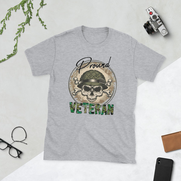 Photos showcase a Stone Gray patriotic graphic t-shirt featuring a distressed military-inspired skull artwork with tactical helmet details, camouflage typography, rugged Americana styling, and bold veteran-themed graphics. Product images highlight high-resolution DTF printing, edgy patriotic aesthetics, vintage military-inspired textures, and oversized front graphic placement designed for comfortable everyday wear.