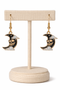 A curated set of Mystic Charm earrings featuring intricate, gothic-inspired designs with enamel detailing and gold-tone hooks. Styled across a mix of clean product shots and moody, aesthetic backgrounds, this collection blends dark elegance with a mystical edge. Each piece showcases unique character and craftsmanship, perfect for adding a bold, alternative statement to any look.