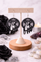 A curated collection of witchy-inspired acrylic earrings featuring dark, mystical designs including celestial symbols, occult figures, crystal shapes, and gothic motifs. Each pair showcases bold black detailing paired with soft lavender accents, displayed in styled scenes with crystals, candles, and moody textures. The collection blends alternative fashion with mystical aesthetics, creating a cohesive, edgy yet feminine visual