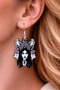 A curated collection of witchy-inspired acrylic earrings featuring dark, mystical designs including celestial symbols, occult figures, crystal shapes, and gothic motifs. Each pair showcases bold black detailing paired with soft lavender accents, displayed in styled scenes with crystals, candles, and moody textures. The collection blends alternative fashion with mystical aesthetics, creating a cohesive, edgy yet feminine visual