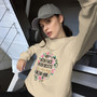 “My Resting Face Never Rests floral wreath crewneck sweatshirt featuring pink flowers and bold statement text on tan sweatshirt, full view showing feminine sarcastic graphic design.”