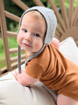 Textured knit baby bonnets in natural undyed baby alpaca wool on 12 month old child.