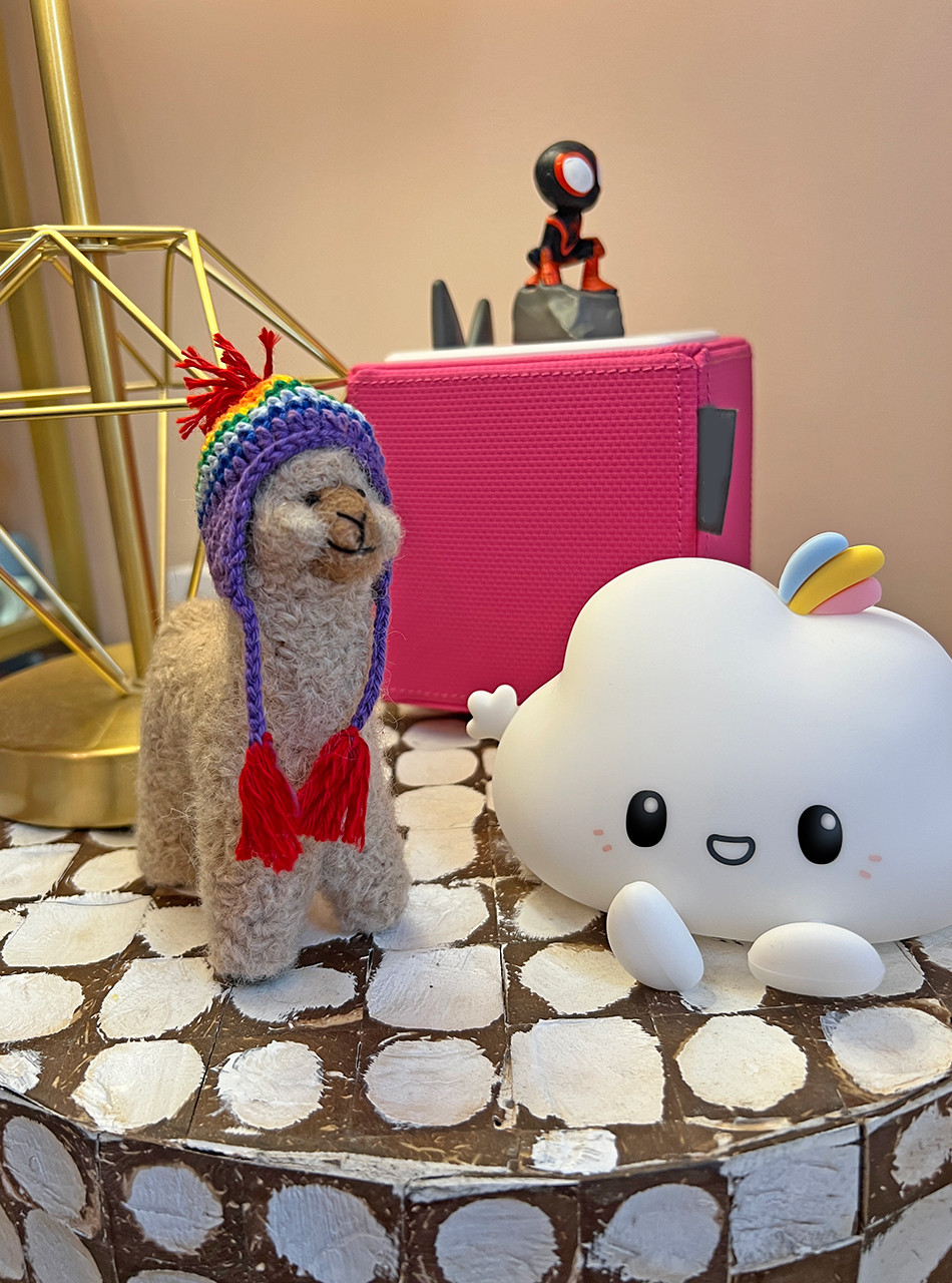 Alpaca Felted Figure with bright hat on nightstand.