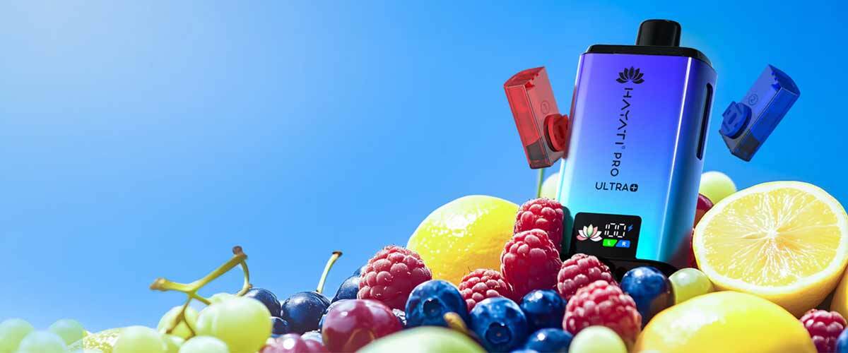 Hayati Pro Ultra Plus vape surrounded by mixed fruits showing dual flavour pods and LED display for the 25K puff big vape.