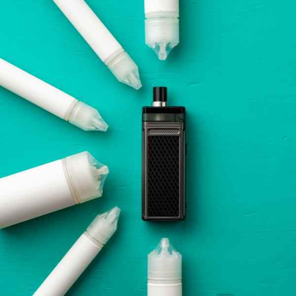 White vape e-liquid bottles around a pod vape device