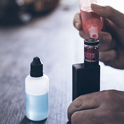 Man Filling Up Vape Tank With E-Liquid Bottle