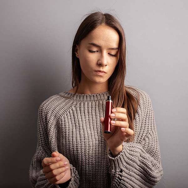 Woman looking disapointed at vape device as its not working correctly