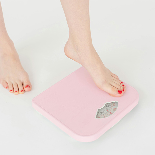 Person stepping on to pink scales for weight monitoring