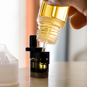Man Topping Up Pod and Wicking Coil With E-Liquid