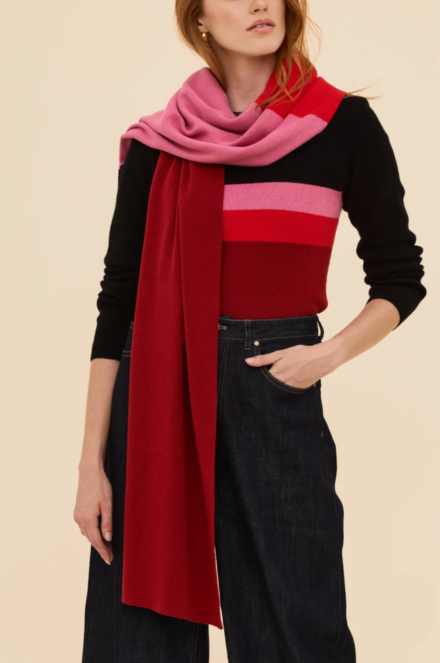 A styled product shot of the Long Play Scarf draped to showcase its bold color-blocked panel design in burgundy, vibrant red, soft pink, and deep black.