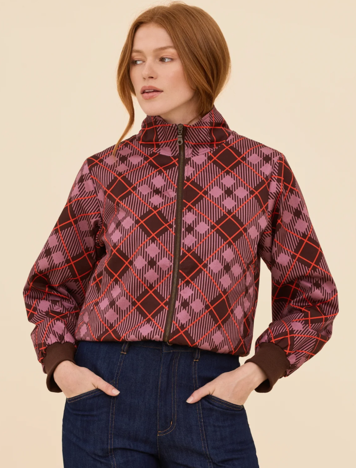 Front view of a model wearing the Renegade Bomber Jacket, showcasing its retro color-blocked panels in deep chocolate, dusty lilac, and red with a front zip closure.