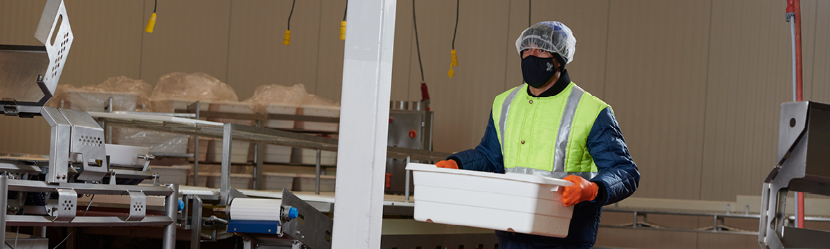 Employee working in cold storage facility wearing insulated safety gear.