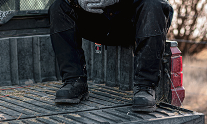 Man with waterproof work boots sitting in a truck bed
