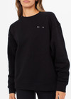 THE UPSIDE women's black Saturn Arrow Sweater is an organic cotton fleece jumper with a relaxed, oversized fit. It features a soft rib at the neckline, handcuffs and cuffs.