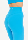 THE UPSIDE Peached 25inch High Midi Pant in Pool Blue is a recycled 25” midi length legging with a V shaped high-rise waistband and printed arrow logo at back.