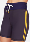 THE UPSIDE women's grey Dunes 5 inch Spin Short is made from recycled textured rib fabrication with moisture wicking properties. The mid-rise spin short are styled with yellow side stripes and drawcord through the waist. Designed for the gym.