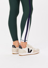 THE UPSIDE women's green Playoff 25 inch High Midi Pant is made from a recycled soft peached fabrication with a brushed handfeel, creating the pant to be breathable and quick drying. The green pant is paired with navy and white for an elevated look. Designed for golf.