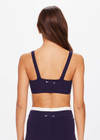THE UPSIDE women's navy Montage Rory Scoop Crop is a knitted cropped sports bra with a scooped neckline and cream side panels for style and soft elastic underbust for comfort. Designed for light movement and recovery.