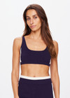 THE UPSIDE women's navy Montage Rory Scoop Crop is a knitted cropped sports bra with a scooped neckline and cream side panels for style and soft elastic underbust for comfort. Designed for light movement and recovery.