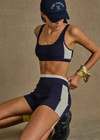 THE UPSIDE women's navy Montage Rory Scoop Crop is a knitted cropped sports bra with a scooped neckline and cream side panels for style and soft elastic underbust for comfort. Designed for light movement and recovery.