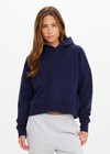 THE UPSIDE women's navy organic cotton Byron Embossed Logo Hoodie is designed for a relaxed boxy fit and features a tonal embossed horseshoe logo on the chest.
