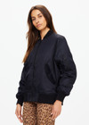THE UPSIDE women's black Tribute Bomber Jacket is made from recycled fabric. The zip up jacket features water resistant coating and pockets. Designed for travel.
