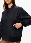 THE UPSIDE women's black Tribute Bomber Jacket is made from recycled fabric. The zip up jacket features water resistant coating and pockets. Designed for travel.