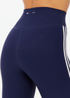 THE UPSIDE women's navy recycled peached Florence Flare Pant is a high-rise pant in a breathable fabric, featuring cream side stripes. Perfect for pilates.